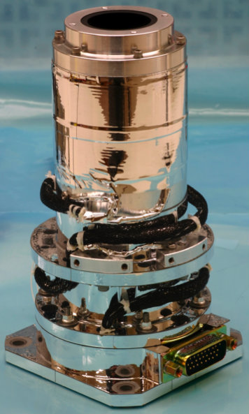 A metal cylinder atop two metal plates, with thick bundles of wires connecting all components and a wide input port at the base.