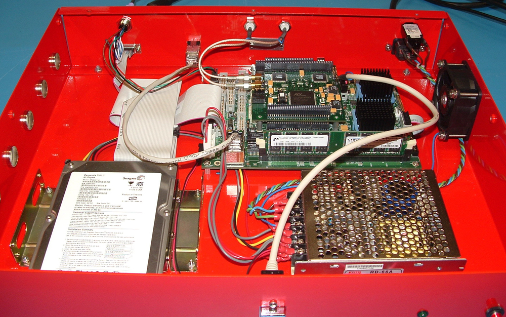 Circuit board and electronic components sit in a bright red box, connected with twisting, multicolored wires. 